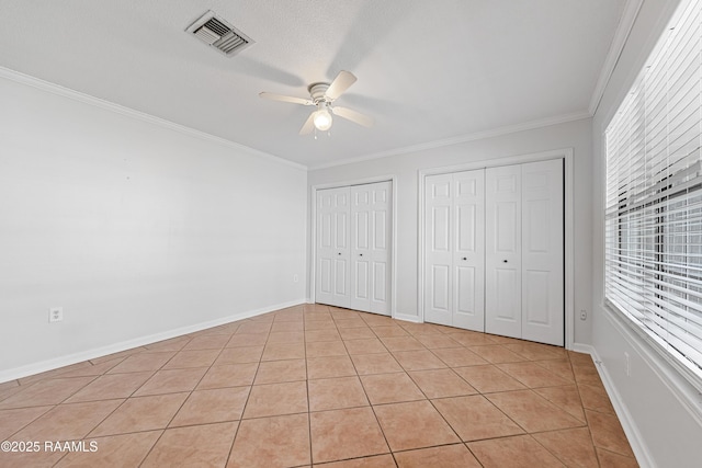 15 Courtyard Cir, Lafayette, LA 70508 - unfurnished bedroom featuring multiple closets, light tile patterned floors, ornamental molding, and a ceiling fan
