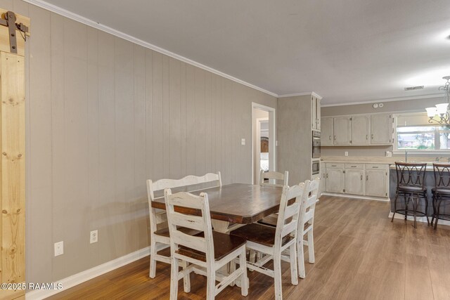 209 Sandager Ave, Jeanerette, LA 70544 - dining space with light wood-style flooring, ornamental molding, a chandelier, and a barn door