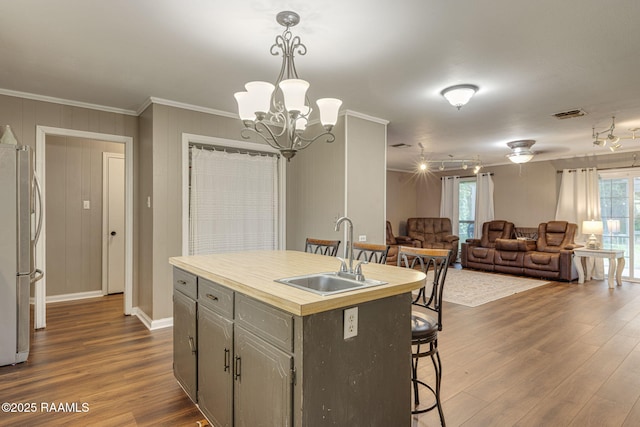 209 Sandager Ave, Jeanerette, LA 70544 - kitchen with freestanding refrigerator, dark wood-style flooring, crown molding, gray cabinets, and a kitchen bar