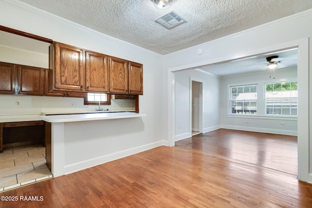 707 Compton St, New Iberia, LA 70560 - kitchen featuring a textured ceiling, plenty of natural light, light wood finished floors, light countertops, and ornamental molding