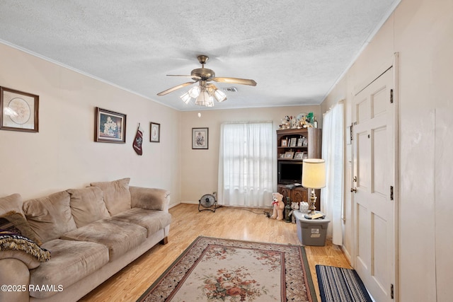 701 Ledoux St, Jennings, LA 70546 - living room featuring a ceiling fan, a textured ceiling, light wood-style floors, and crown molding
