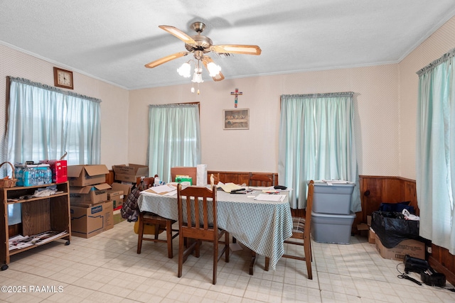 701 Ledoux St, Jennings, LA 70546 - dining room featuring ornamental molding, ceiling fan, a wainscoted wall, light floors, and wooden walls