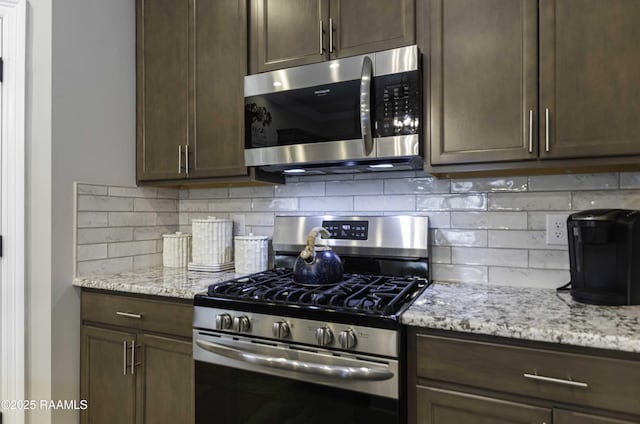 100 Rose Of Sharon Ln, Lafayette, LA 70508 - kitchen featuring stainless steel appliances, dark brown cabinetry, tasteful backsplash, and light stone countertops