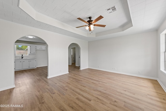 189 Jeremy Rd, Opelousas, LA 70570 - spare room featuring arched walkways, a raised ceiling, ceiling fan, light wood finished floors, and ornamental molding