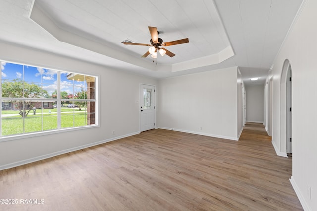 189 Jeremy Rd, Opelousas, LA 70570 - empty room with a tray ceiling, light wood finished floors, a ceiling fan, and arched walkways