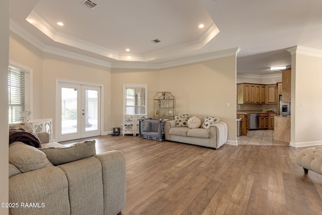 742 Hummingbird Ln, New Iberia, LA 70563 - living room featuring light wood-style flooring, a tray ceiling, crown molding, and french doors