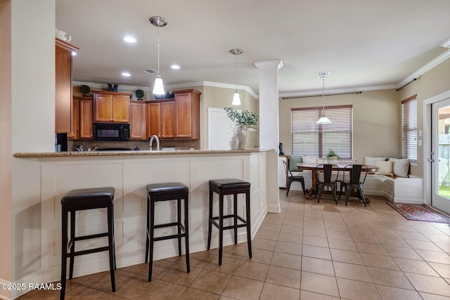 201 Spanish Moss Ln, Broussard, LA 70518 - kitchen featuring black microwave, crown molding, a kitchen breakfast bar, brown cabinetry, and backsplash