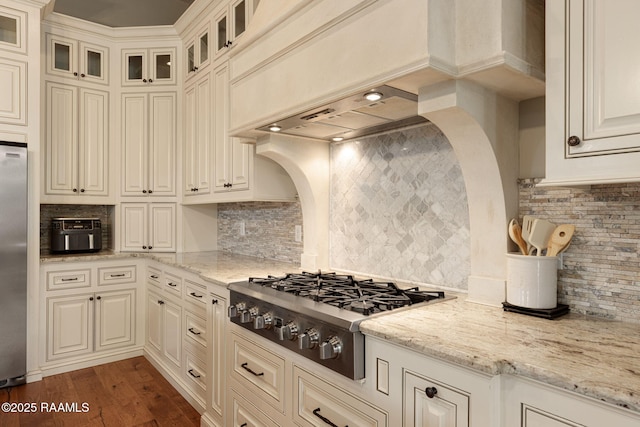 301 Gleneagles Cir, Broussard, LA 70518 - kitchen featuring decorative backsplash, stainless steel appliances, extractor fan, light stone counters, and glass insert cabinets