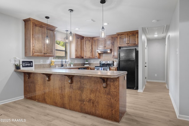 1404 Howard St, New Iberia, LA 70563 - kitchen with freestanding refrigerator, electric range, under cabinet range hood, a peninsula, and brown cabinetry