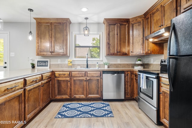 1404 Howard St, New Iberia, LA 70563 - kitchen featuring appliances with stainless steel finishes, under cabinet range hood, light wood-style flooring, decorative light fixtures, and recessed lighting