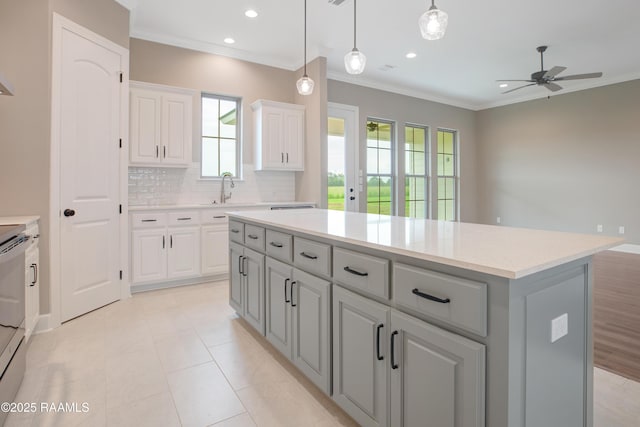 11511 Baker Senior Dr, Abbeville, LA 70510 - kitchen with a center island, ceiling fan, ornamental molding, tasteful backsplash, and white cabinetry