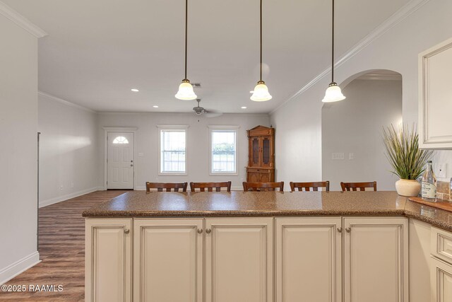 7804 Picard Rd, Maurice, LA 70555 - kitchen featuring wood finished floors, ornamental molding, arched walkways, cream cabinets, and decorative light fixtures