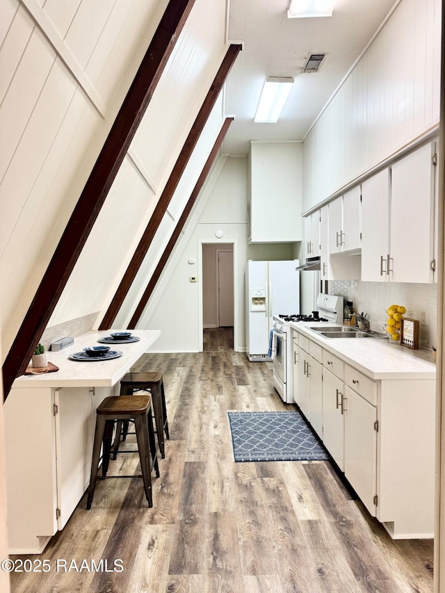 607 Ernest St, New Iberia, LA 70563 - kitchen with white appliances, light wood finished floors, white cabinets, light countertops, and decorative backsplash