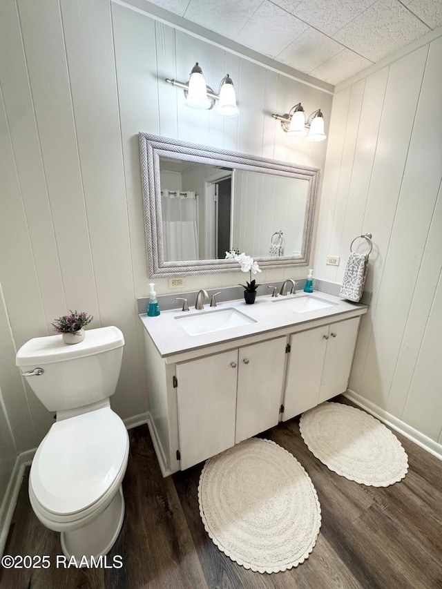 607 Ernest St, New Iberia, LA 70563 - bathroom featuring double vanity, wood finished floors, and a decorative wall