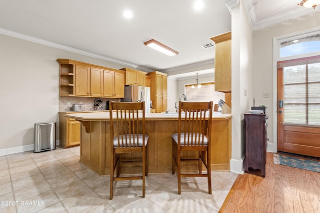 117 Montero Cir, Lafayette, LA 70503 - kitchen featuring stainless steel fridge with ice dispenser, ornamental molding, light countertops, a peninsula, and a breakfast bar