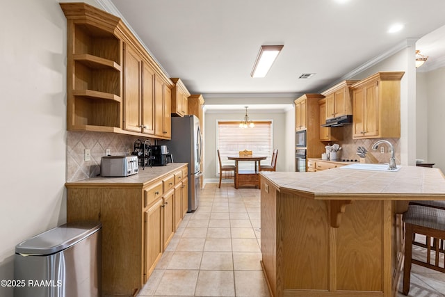 117 Montero Cir, Lafayette, LA 70503 - kitchen featuring tile counters, under cabinet range hood, a peninsula, a breakfast bar area, and ornamental molding