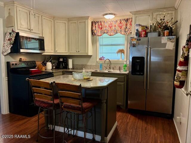 105 Sugar Dr, Broussard, LA 70518 - kitchen featuring stainless steel appliances, dark wood finished floors, light countertops, a kitchen island, and a breakfast bar