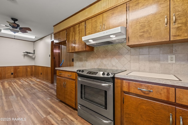 1212 S Main St, Breaux Bridge, LA 70517 - kitchen with stainless steel electric range oven, under cabinet range hood, brown cabinets, light countertops, and a wainscoted wall