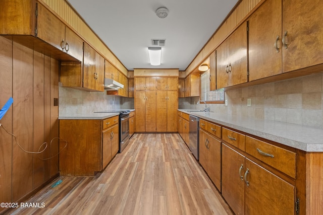 1212 S Main St, Breaux Bridge, LA 70517 - kitchen featuring stainless steel appliances, under cabinet range hood, light wood-style flooring, brown cabinets, and light countertops