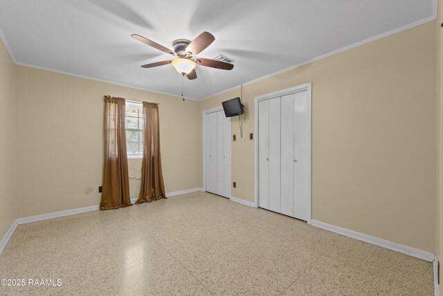 1212 S Main St, Breaux Bridge, LA 70517 - unfurnished bedroom featuring two closets, speckled floor, ornamental molding, and ceiling fan