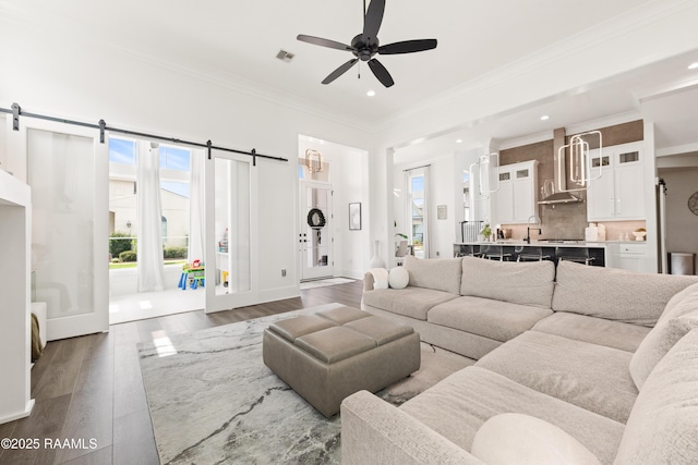 100 Catamaran Dr, Youngsville, LA 70592 - living area with a barn door, healthy amount of natural light, wood finished floors, recessed lighting, and crown molding
