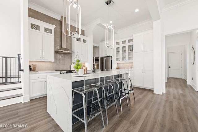100 Catamaran Dr, Youngsville, LA 70592 - kitchen with freestanding refrigerator, a center island with sink, white cabinetry, wall chimney exhaust hood, and recessed lighting