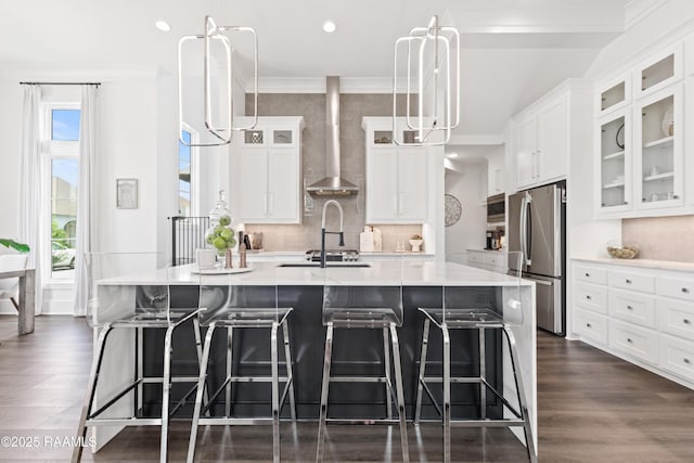 100 Catamaran Dr, Youngsville, LA 70592 - kitchen with stainless steel appliances, wall chimney range hood, an island with sink, light countertops, and white cabinetry