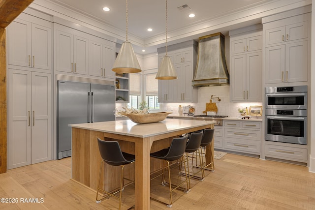 106 Sonoma Way, Lafayette, LA 70508 - kitchen featuring custom exhaust hood, stainless steel appliances, light countertops, light wood-style flooring, and ornamental molding