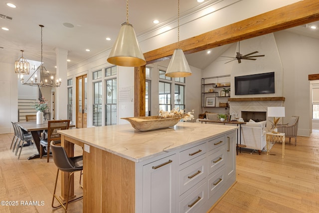 106 Sonoma Way, Lafayette, LA 70508 - kitchen with a kitchen island, a fireplace, light wood-type flooring, a chandelier, and decorative light fixtures
