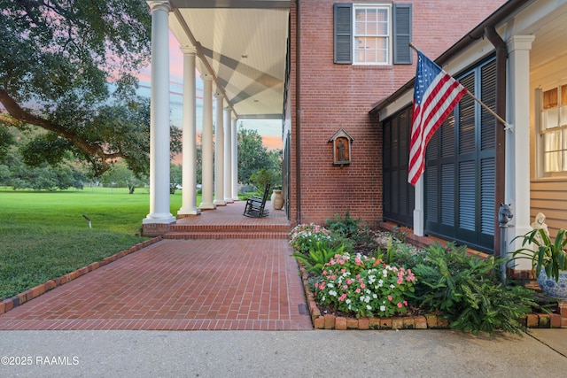 6302 Old Jeanerette Rd, New Iberia, LA 70563 - view of exterior entry featuring a lawn, brick siding, and a porch