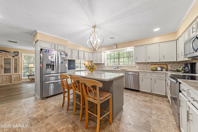 118 Garrigue Dr, Opelousas, LA 70570 - kitchen featuring stainless steel appliances, a chandelier, a center island, a textured ceiling, and tasteful backsplash