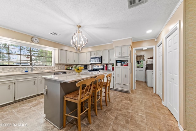 118 Garrigue Dr, Opelousas, LA 70570 - kitchen with appliances with stainless steel finishes, ornamental molding, a chandelier, a kitchen island, and a breakfast bar area