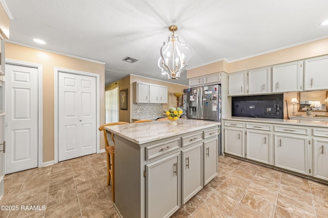 118 Garrigue Dr, Opelousas, LA 70570 - kitchen featuring stainless steel fridge with ice dispenser, a chandelier, decorative backsplash, crown molding, and a kitchen island