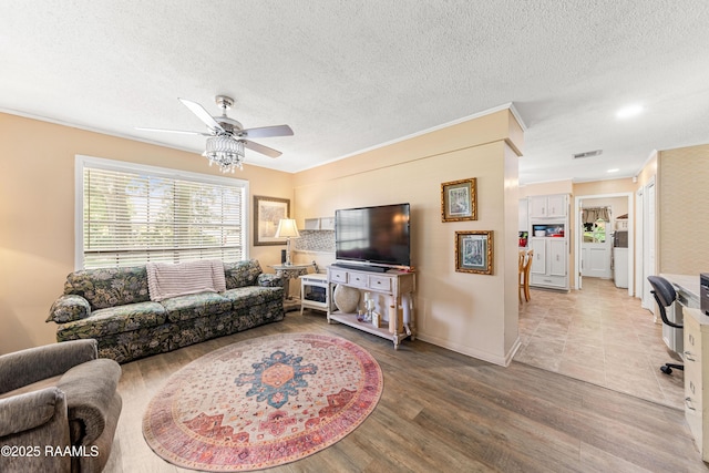118 Garrigue Dr, Opelousas, LA 70570 - living area with ceiling fan, wood finished floors, a textured ceiling, and washing machine and clothes dryer