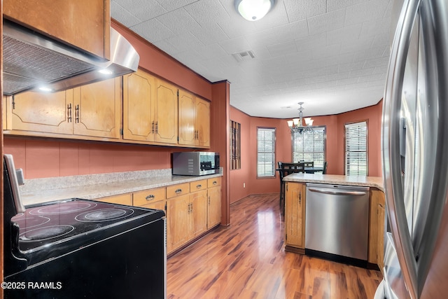 307 Bertrand Rd, Opelousas, LA 70570 - kitchen with appliances with stainless steel finishes, wall chimney range hood, light countertops, light wood-style floors, and a chandelier