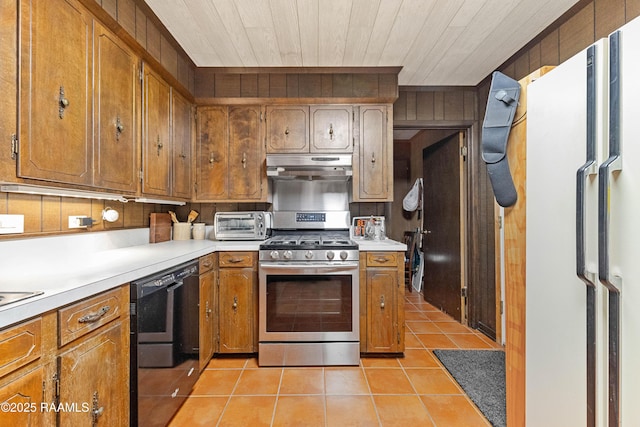 1912 Mimosa St, Abbeville, LA 70510 - kitchen featuring gas range, under cabinet range hood, freestanding refrigerator, light tile patterned flooring, and brown cabinetry