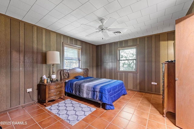 1912 Mimosa St, Abbeville, LA 70510 - bedroom featuring multiple windows, light tile patterned floors, wood walls, and a ceiling fan