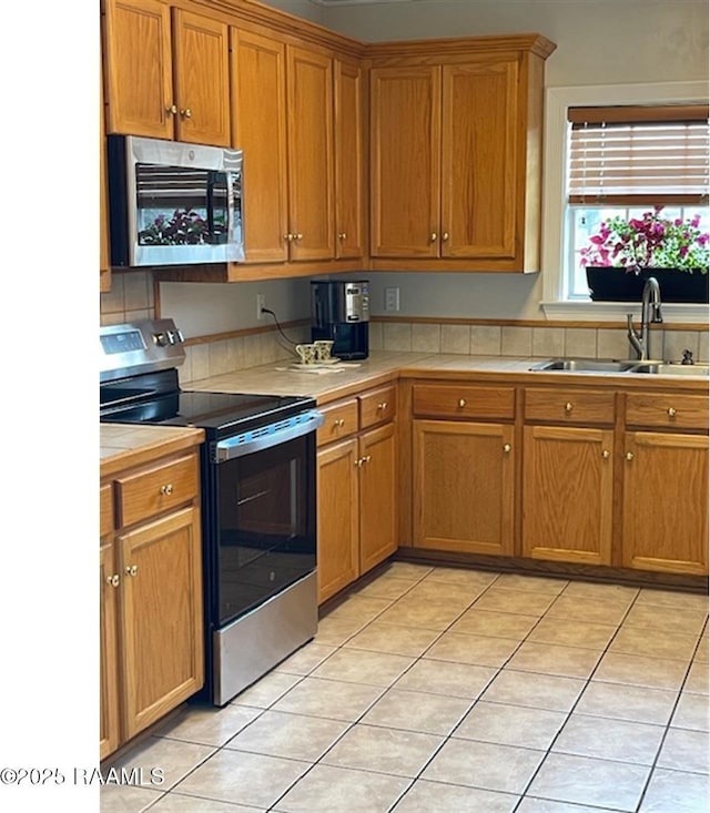101 Asphodel Ct, Lafayette, LA 70503 - kitchen with stainless steel appliances, light tile patterned floors, brown cabinetry, and tile counters