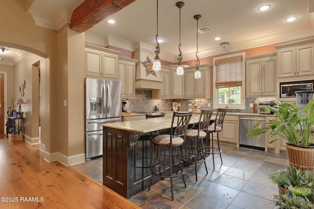 104 Littleton Xing, Lafayette, LA 70508 - kitchen featuring appliances with stainless steel finishes, cream cabinets, arched walkways, backsplash, and crown molding