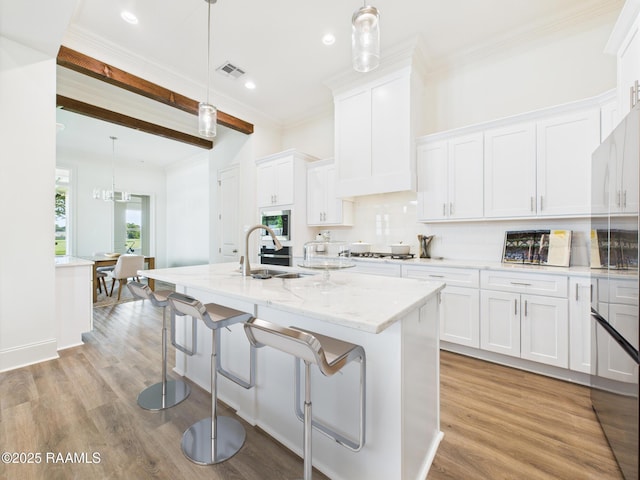 207 Timber Mill St, Lafayette, LA 70508 - kitchen featuring white cabinetry, a center island with sink, backsplash, light wood-type flooring, and crown molding