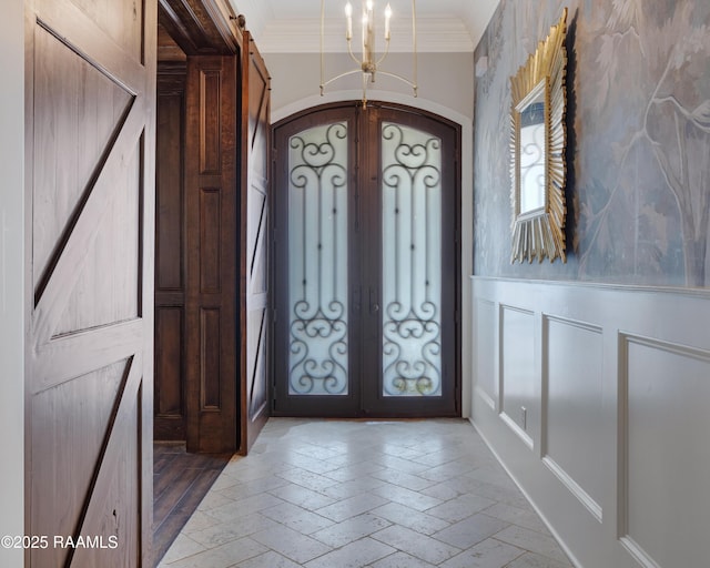 506 Terrell Ct, New Iberia, LA 70563 - foyer with ornamental molding, arched walkways, french doors, a chandelier, and a wainscoted wall