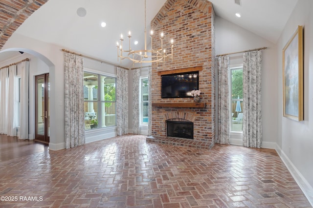 506 Terrell Ct, New Iberia, LA 70563 - unfurnished living room with a brick fireplace, a chandelier, high vaulted ceiling, arched walkways, and brick floors
