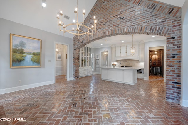 506 Terrell Ct, New Iberia, LA 70563 - kitchen featuring brick floors, a chandelier, open floor plan, arched walkways, and high vaulted ceiling