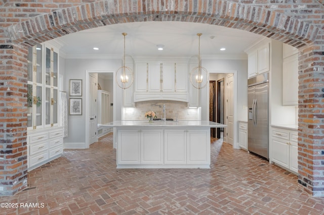 506 Terrell Ct, New Iberia, LA 70563 - kitchen featuring built in refrigerator, light countertops, ornamental molding, white cabinets, and brick floors