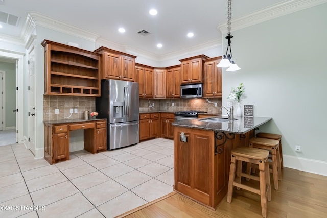 100 Serenity Sound Dr, Lafayette, LA 70506 - kitchen with stainless steel appliances, brown cabinets, a peninsula, ornamental molding, and dark stone counters