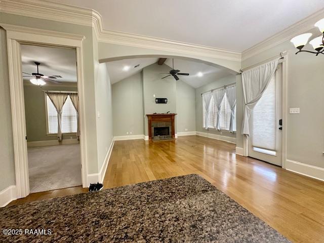 100 Serenity Sound Dr, Lafayette, LA 70506 - unfurnished living room featuring a ceiling fan, arched walkways, wood finished floors, a fireplace with flush hearth, and a chandelier