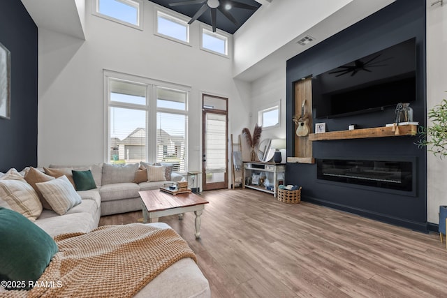 127 Lakes Edge Dr, Broussard, LA 70518 - living area with a ceiling fan, a towering ceiling, wood finished floors, plenty of natural light, and a glass covered fireplace
