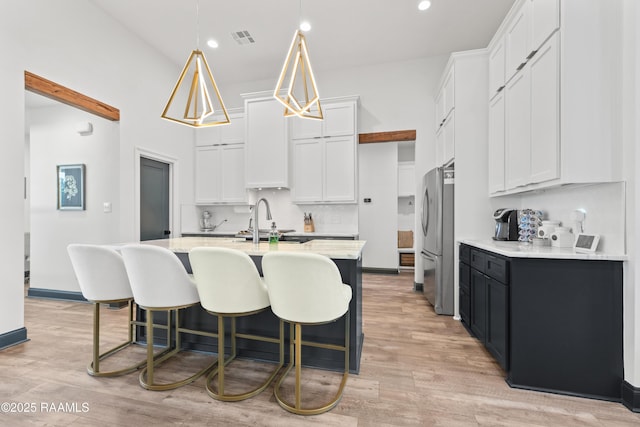 127 Lakes Edge Dr, Broussard, LA 70518 - kitchen featuring freestanding refrigerator, a breakfast bar area, white cabinetry, light wood-style flooring, and recessed lighting