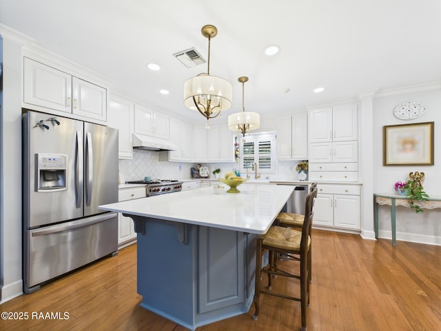 109 Canterbury Rd, Lafayette, LA 70503 - kitchen featuring appliances with stainless steel finishes, white cabinets, crown molding, a chandelier, and wood finished floors