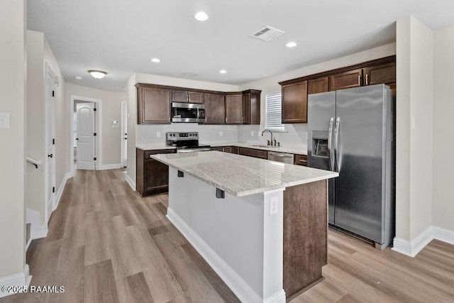 115 Sandstone Ave, Scott, LA 70583 - kitchen featuring stainless steel appliances, dark brown cabinets, a kitchen island, light wood-style floors, and backsplash